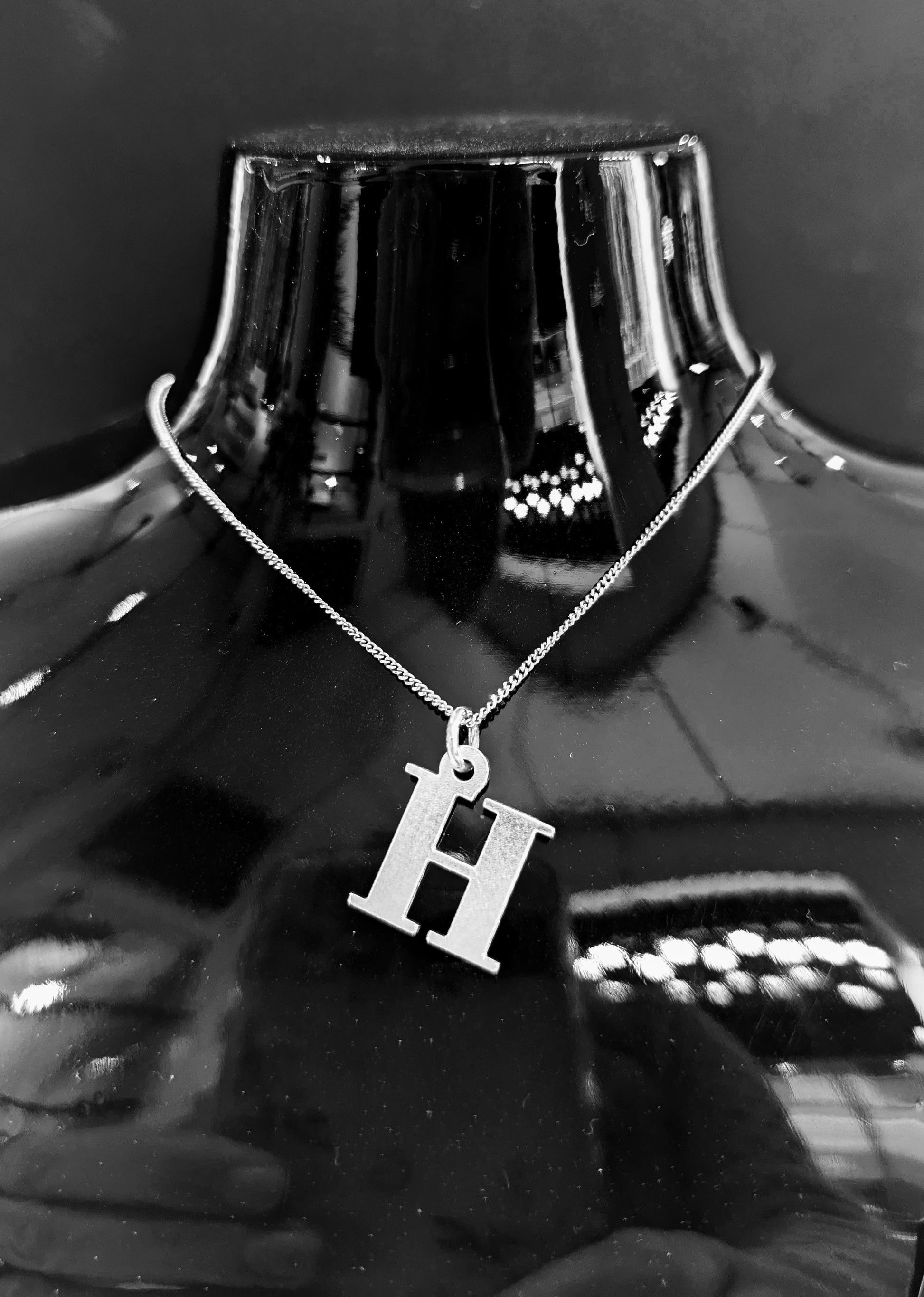 Custom laser-cut silver letter H pendant.